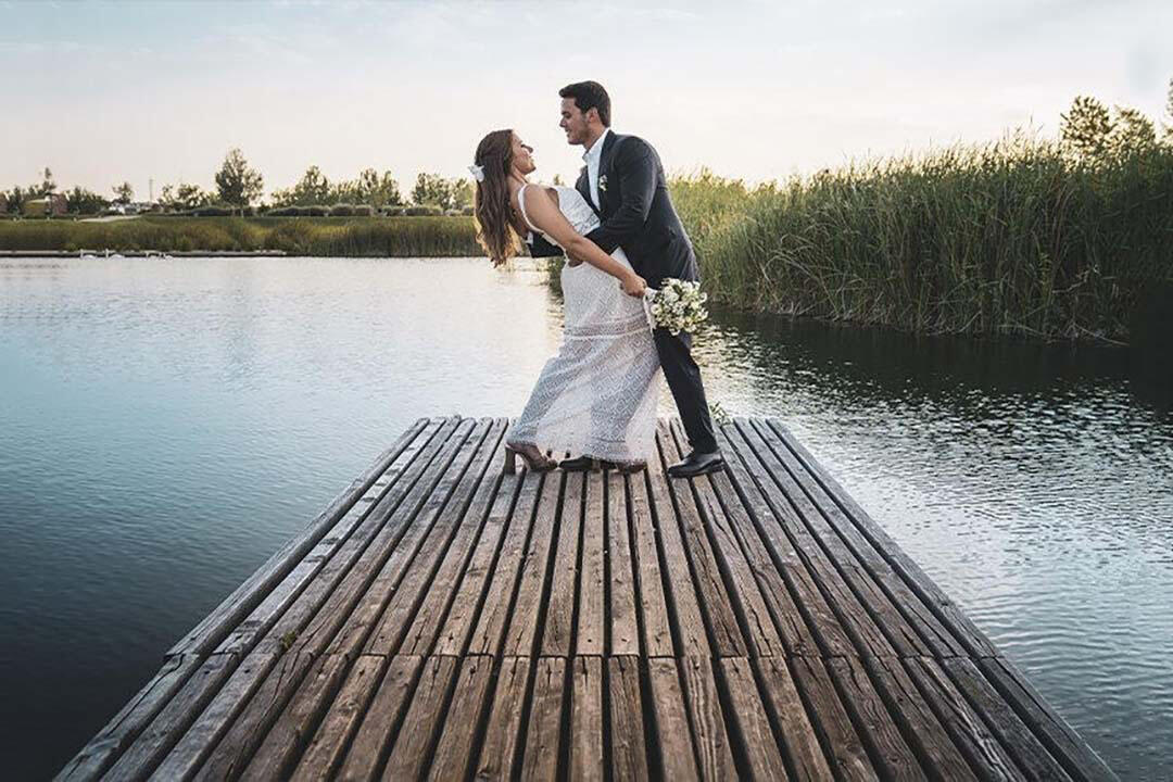 Pareja de recién casados mirándose el uno al otro en una pasarela sobre un lago.